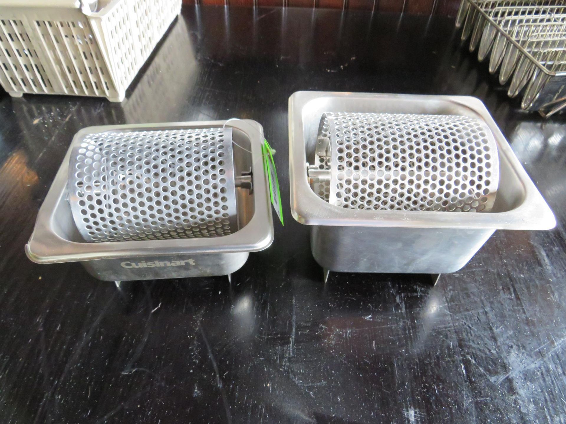 Two stainless steel Cuisinart food roasters with rotating mesh cylinders, on a dark table.