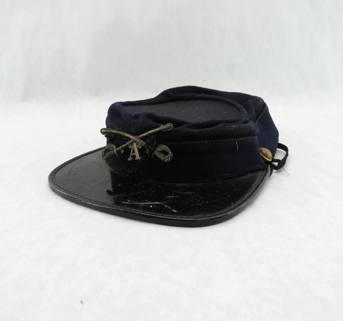 Civil War kepi hat with a dark blue crown, black brim, and crossed rifles insignia.