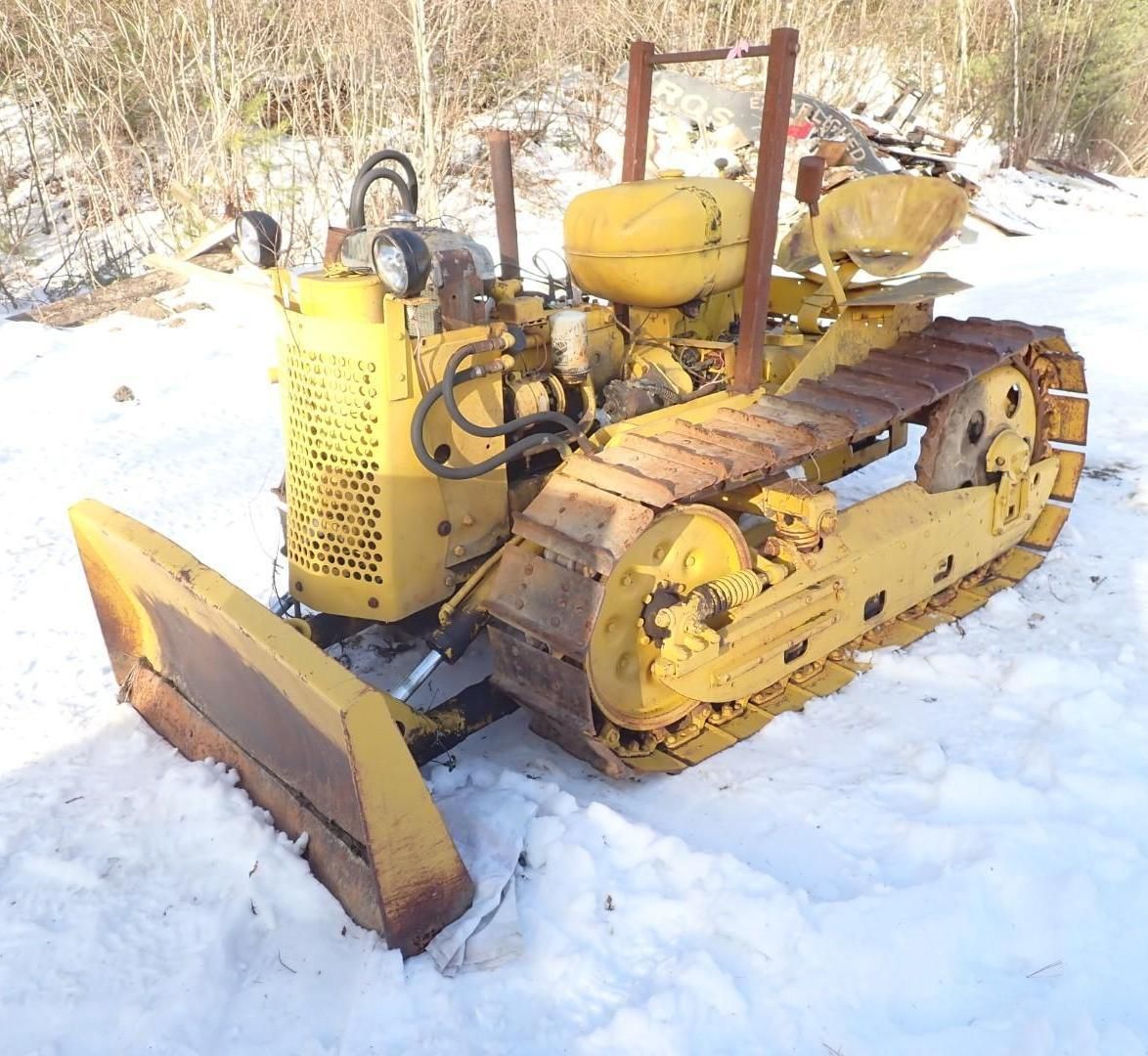 Yellow Oliver Crawler Bulldog with a blade and tracks, in a snowy outdoor setting.