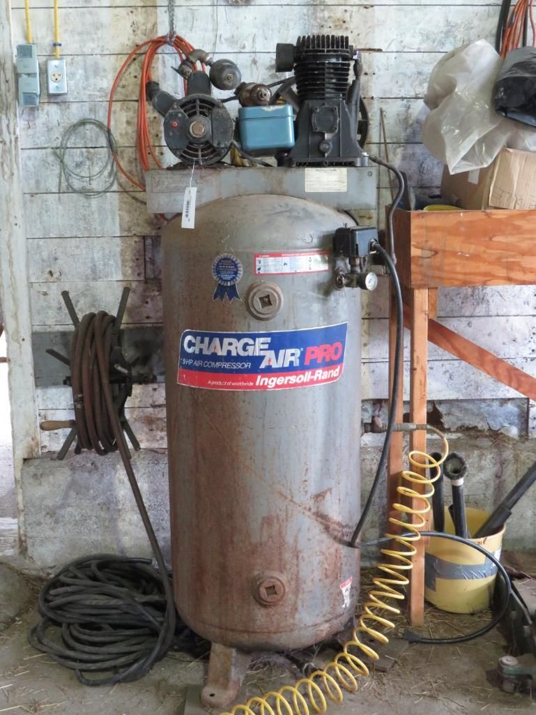 Air compressor, tank, electric motor, coiled hoses, mounted indoors.