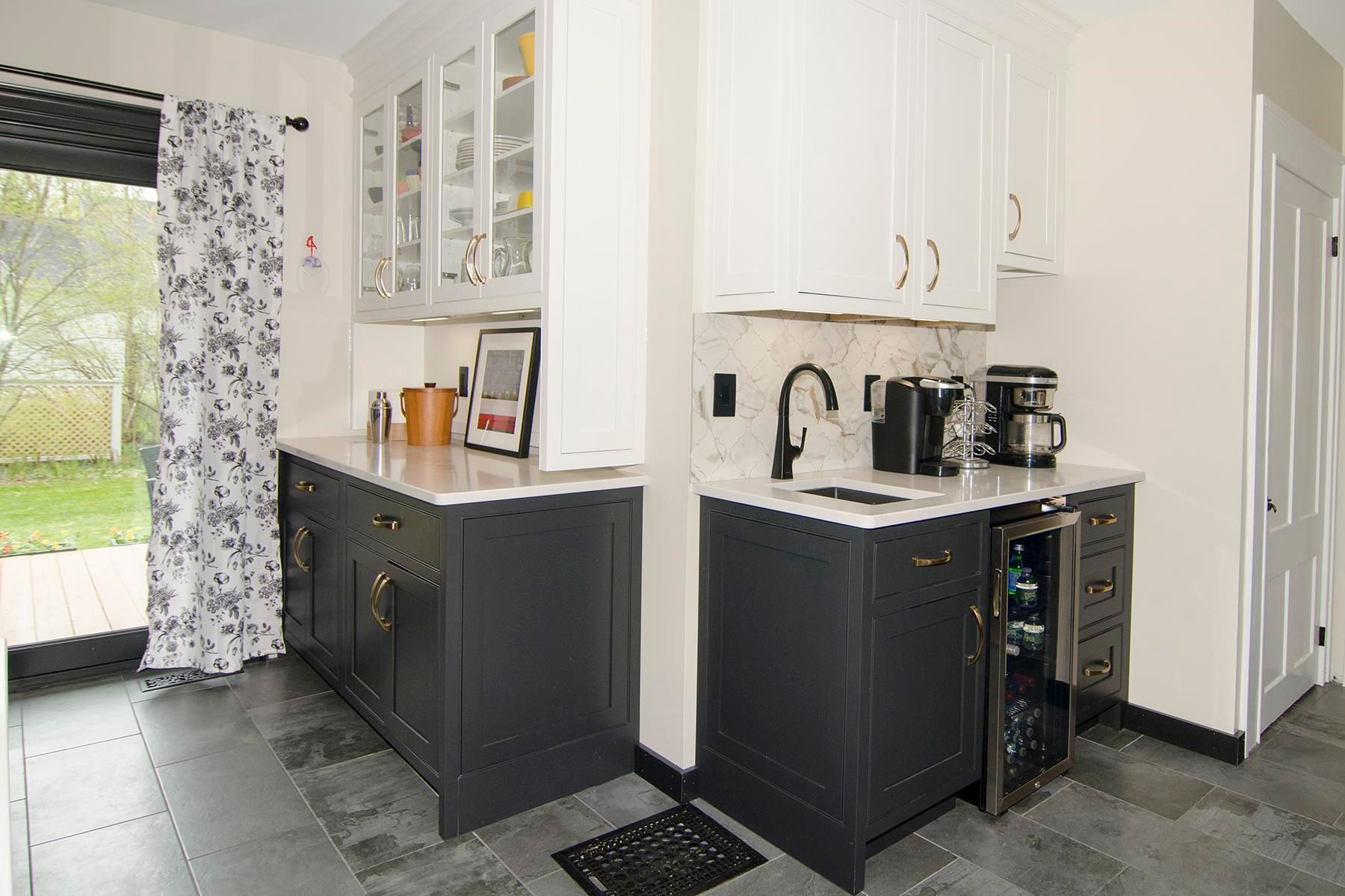 Kitchen with dark gray cabinets, white countertops, and white upper cabinets. A mini-fridge and coffee maker are present.