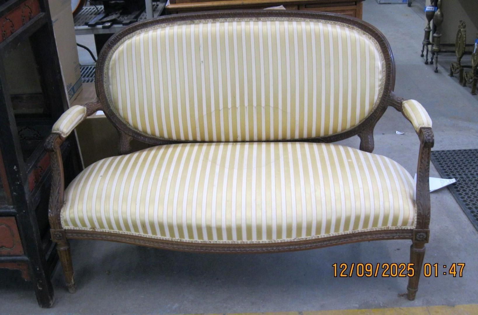Oval-backed, cream-striped love seat with dark wooden frame.