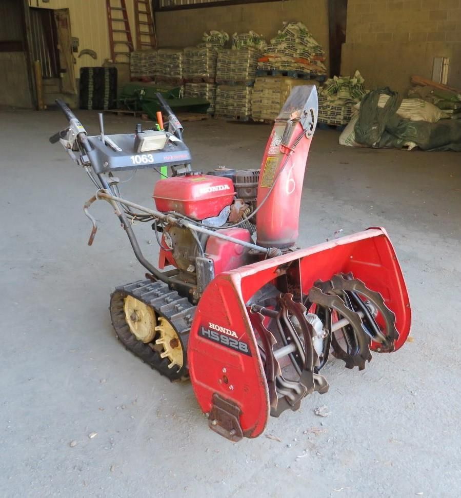 Red Honda HS928 snowblower with tracks, indoors.