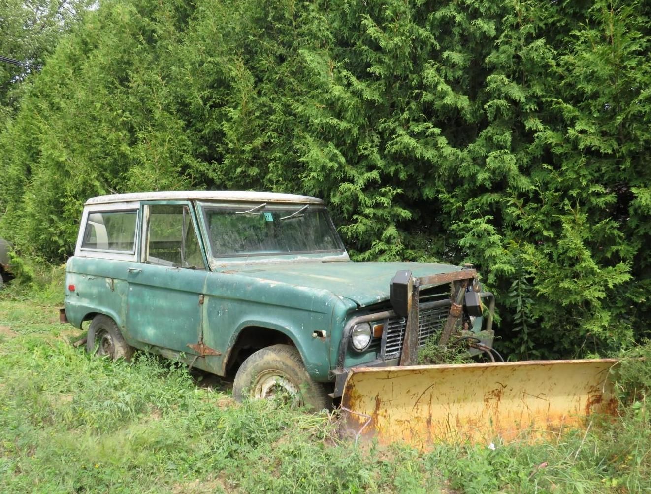 Old, green Ford Bronco with snowplow.