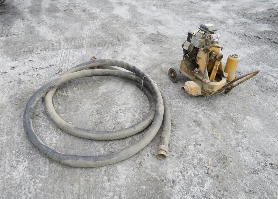 Coiled gray hose and yellow portable pump on a gray concrete surface.