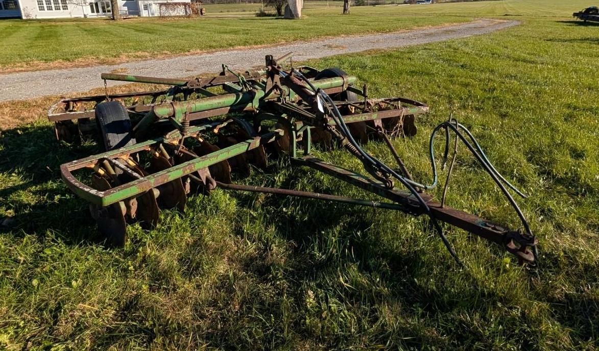 farm implement lying in a grassy field near a dirt road