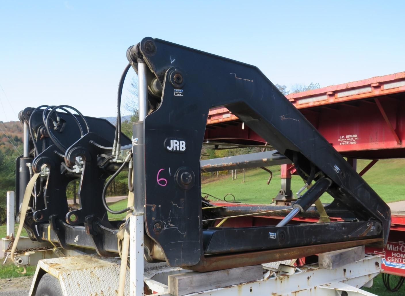 Black JAB log grapple with hydraulic cylinders and 6' marking, mounted on trailer.