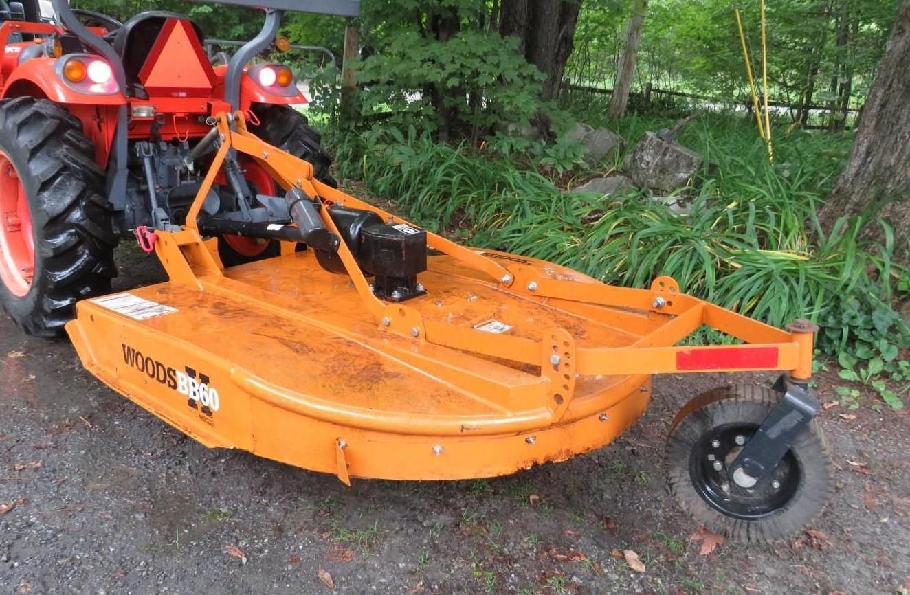 Orange tractor with a rotary cutter mower.