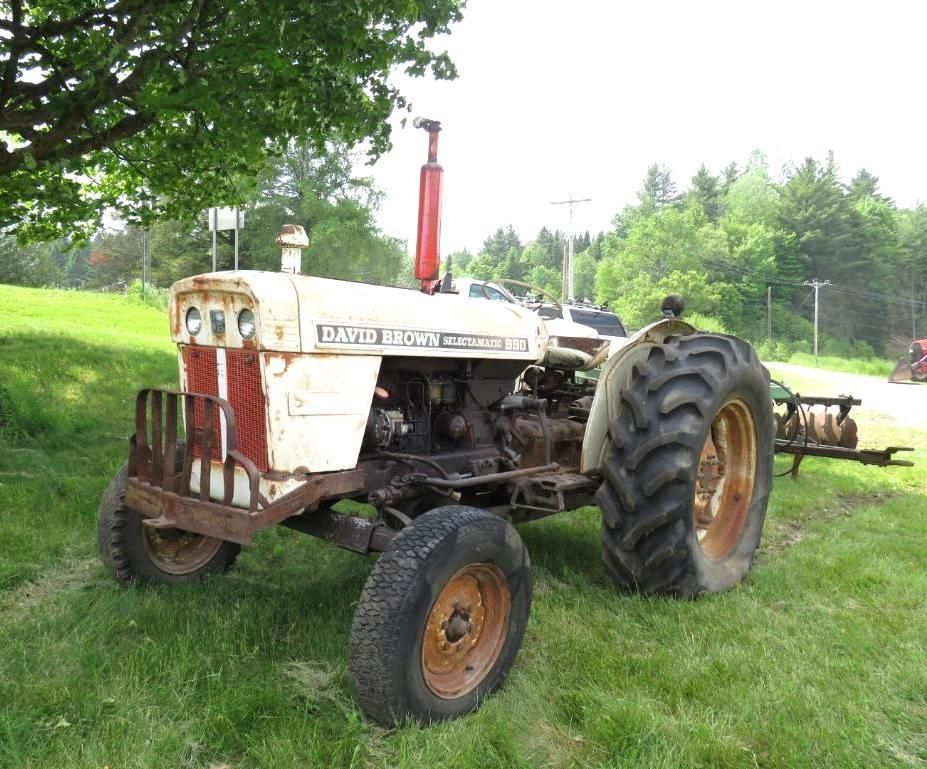 White and brown David Brown tractor on green grass with red exhaust, set in a rural setting.