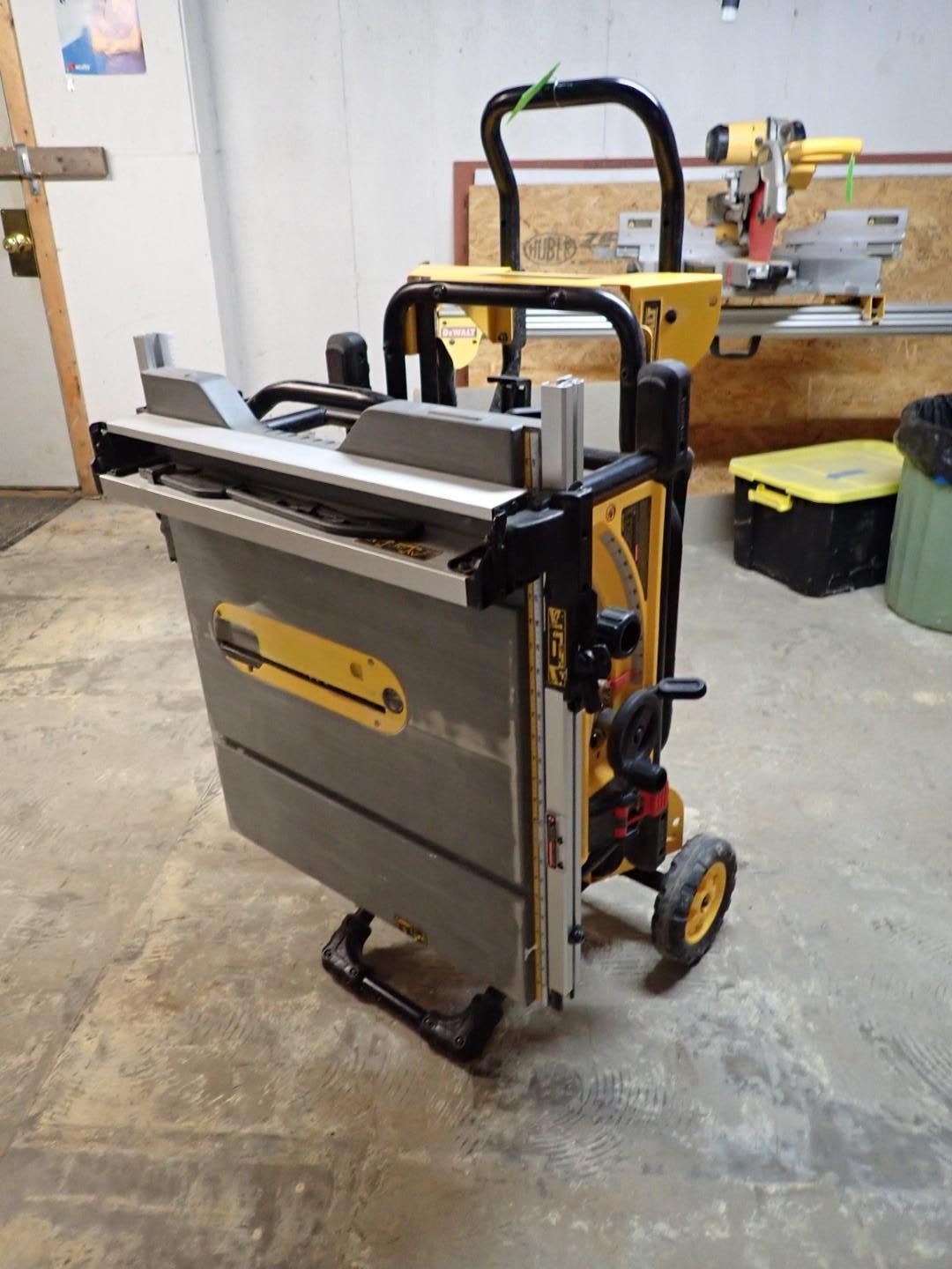 Yellow and gray DeWalt portable table saw with wheels, in a workshop.
