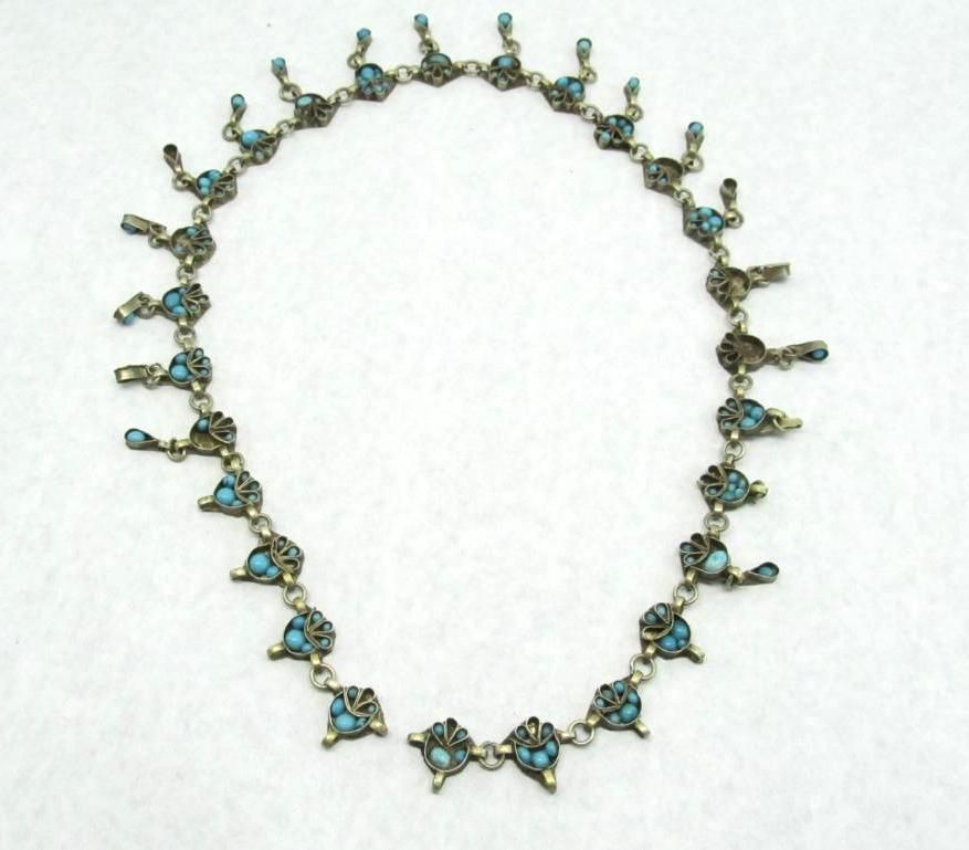 Silver-toned necklace with turquoise-colored stones in an intricate design.
