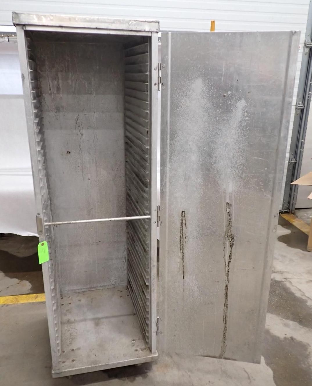 Stainless steel cabinet with open door, showing multiple tray supports. Industrial setting.