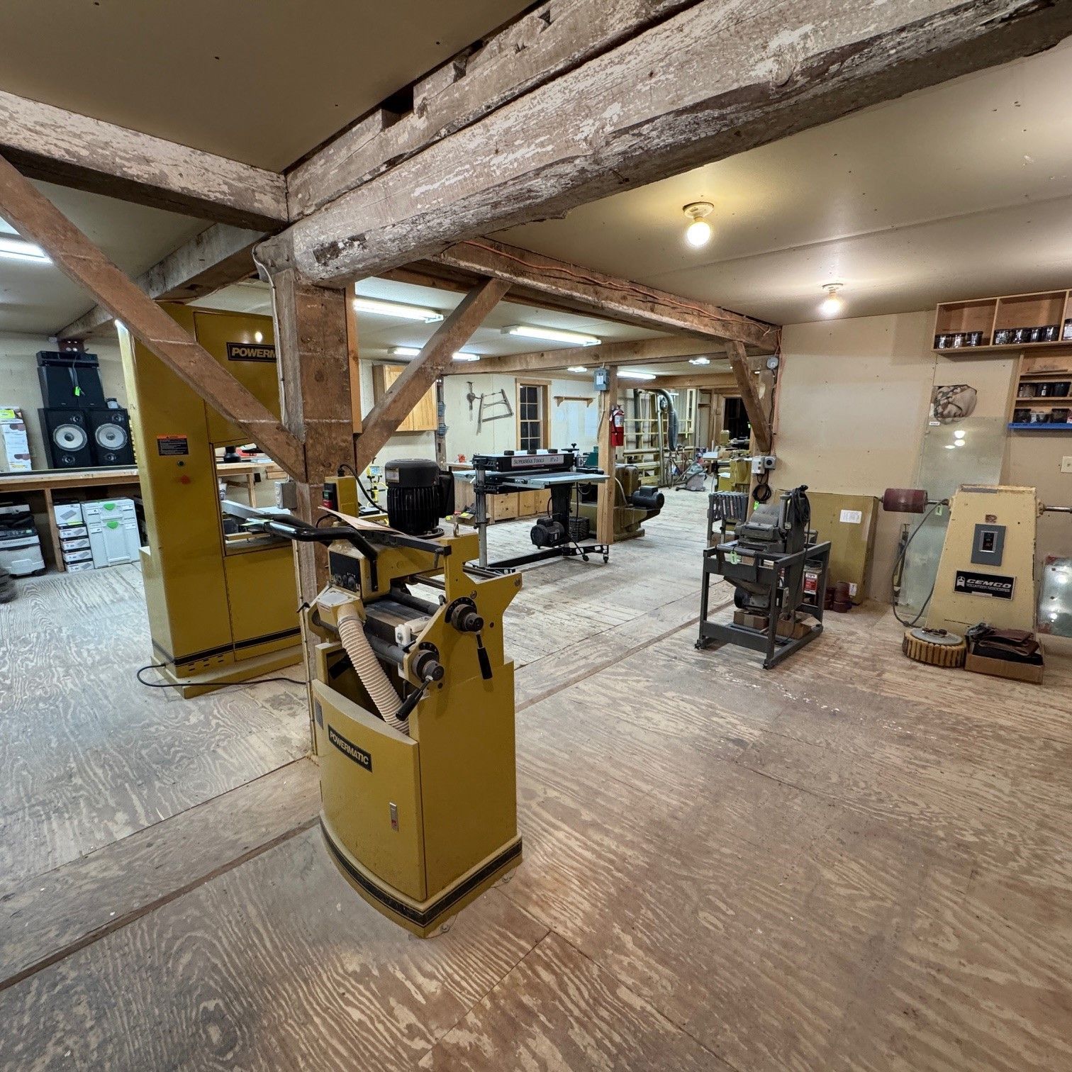 Woodworking shop with large timber beams, tools, and machinery in a spacious industrial interior.