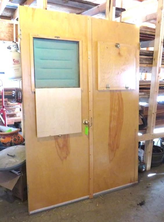 Large wooden doors with windows, a small access panel, and a green tag attached.