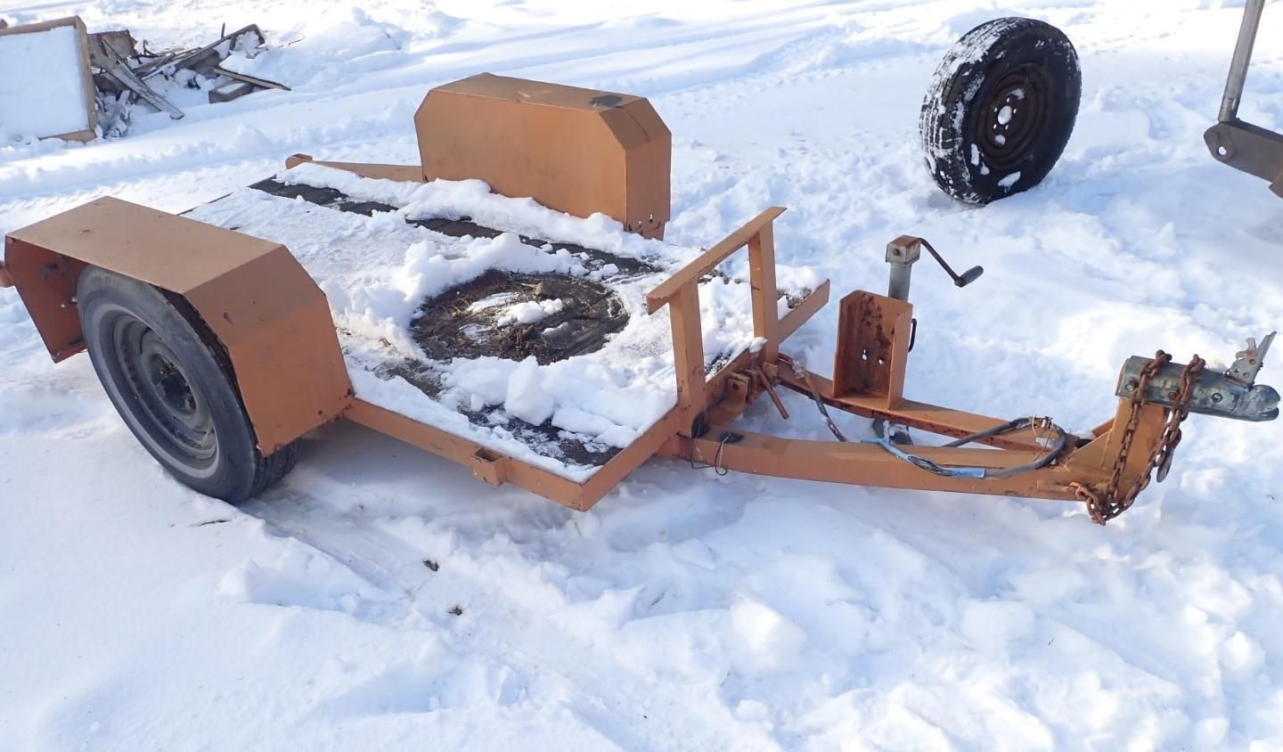 Orange trailer covered in snow, parked outside.