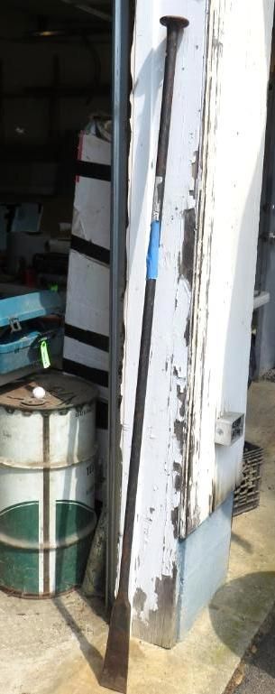 A long metal pry bar leans against a peeling white wall.