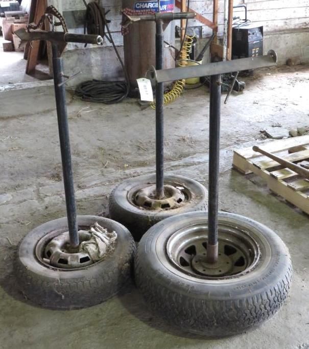 Three metal stands with horizontal bars on top, attached to tires.