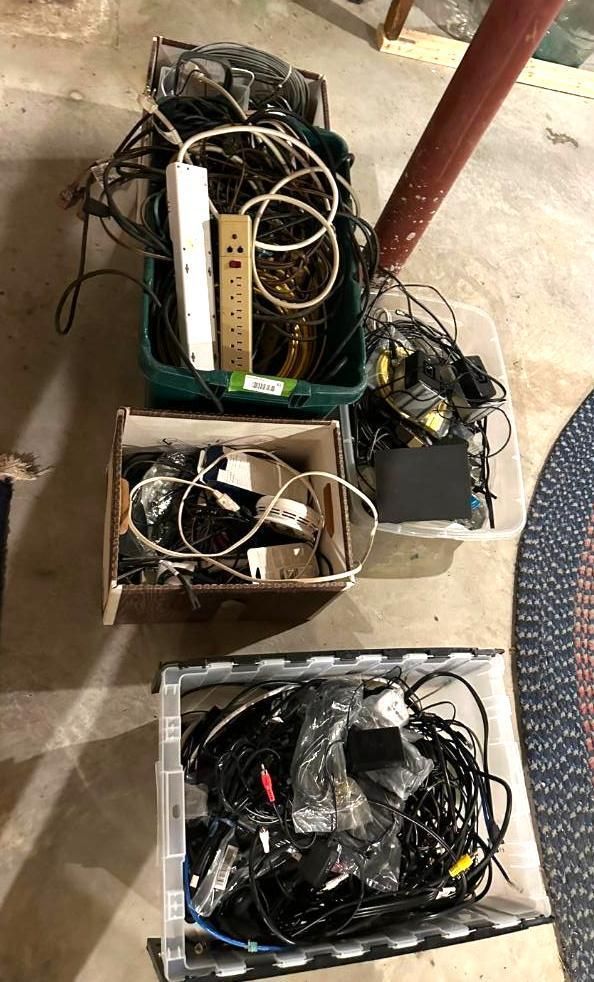 Bins of electronic cables and devices on a concrete floor.