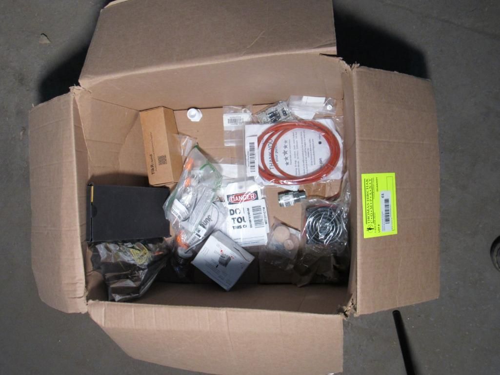 Open cardboard box filled with various automotive parts, including a black box and orange tubing.