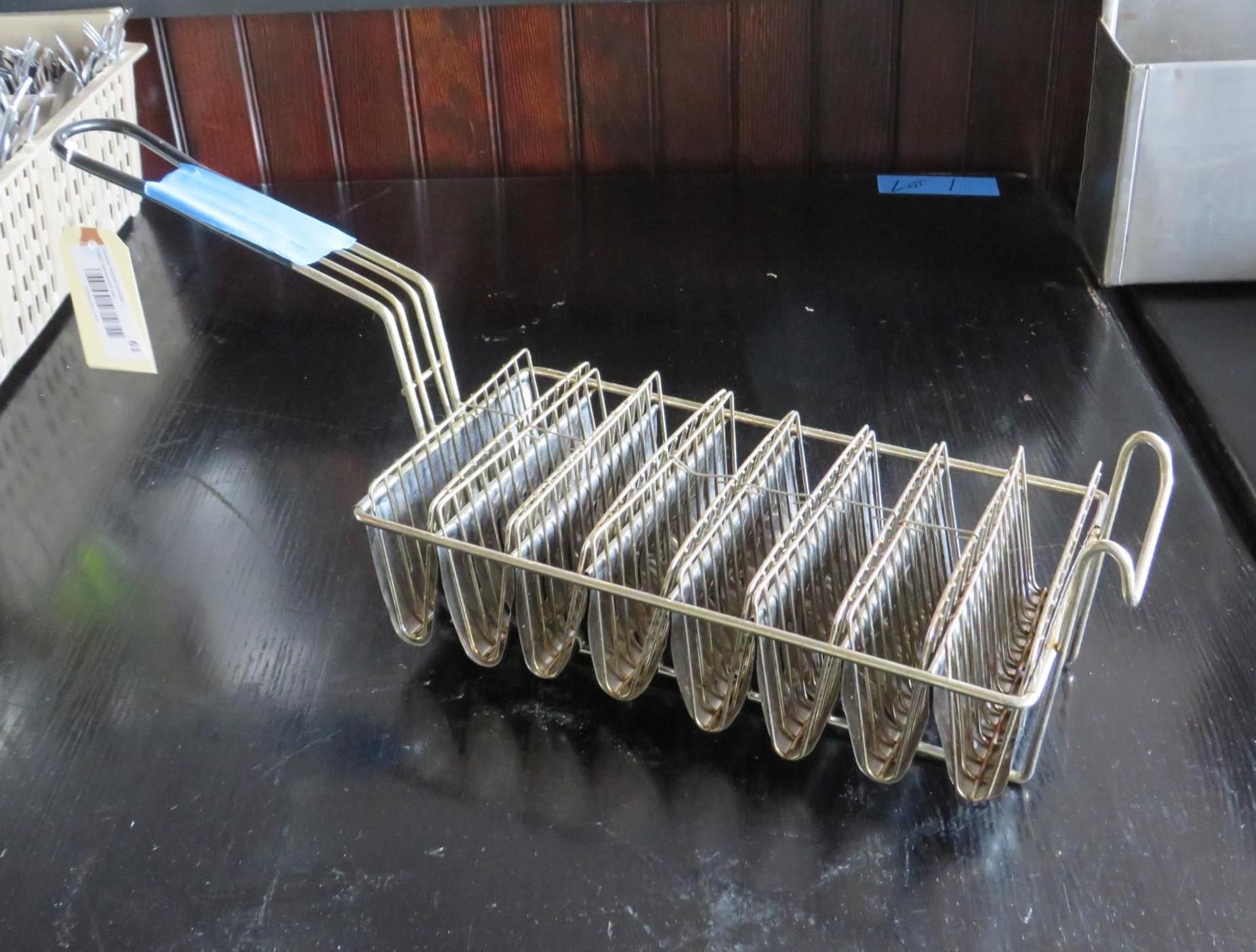 Metal taco holder with blue handle on a dark surface.