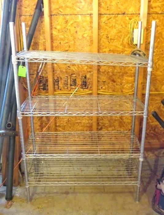 Metal wire shelving unit with four tiers, set against a wooden wall in a garage.