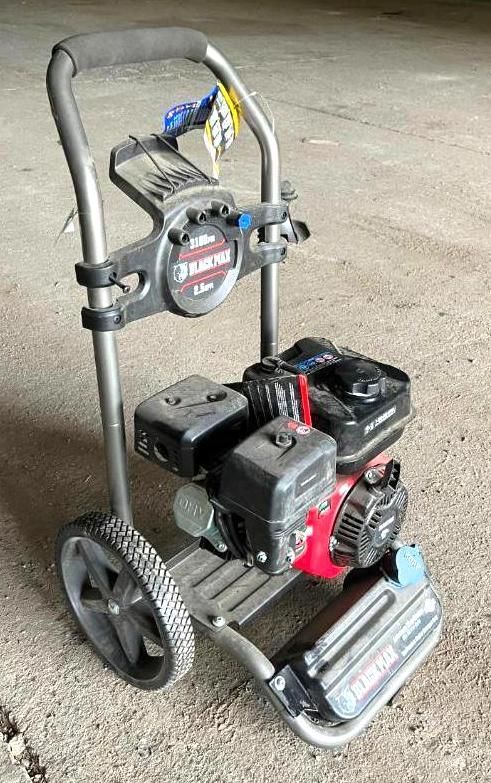 Gas-powered pressure washer with red engine and gray frame on a concrete surface.