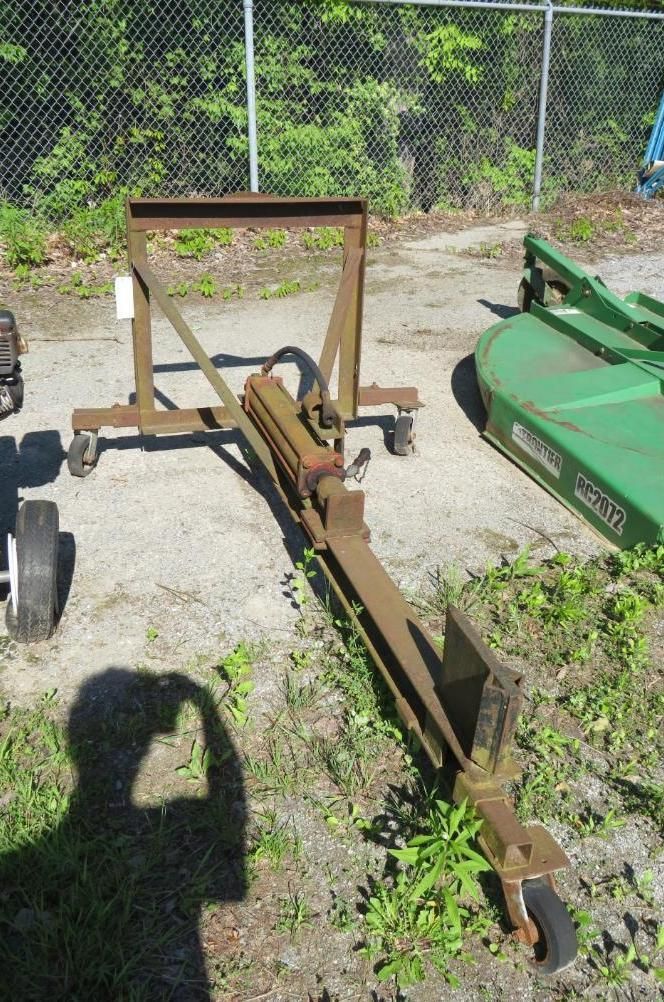 A metal trailer with a hydraulic lift and wheels stands outside.
