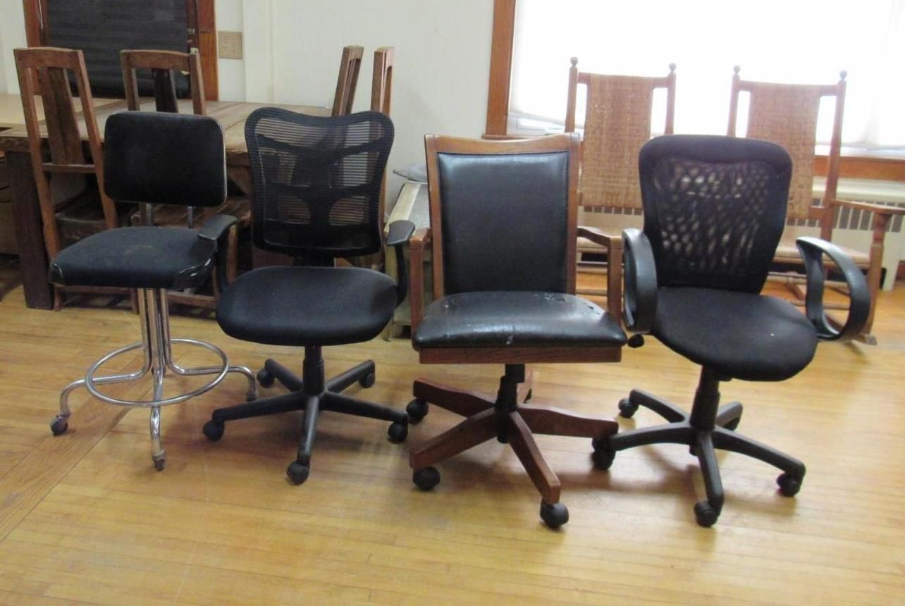 Four black office chairs of varying designs, set against a wooden background.