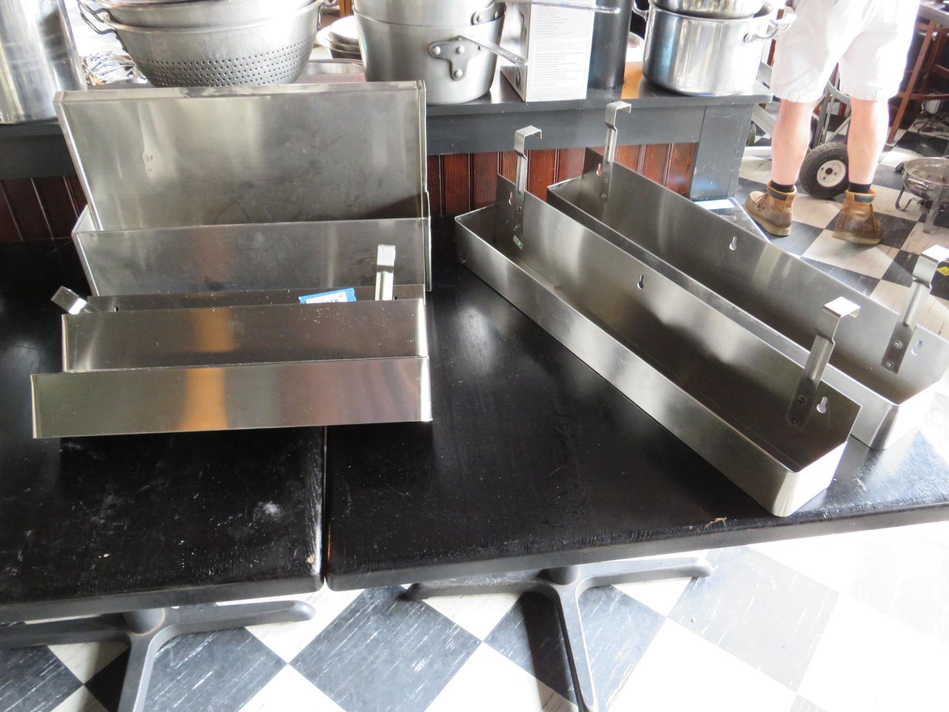 Stainless steel food service containers on black tables.
