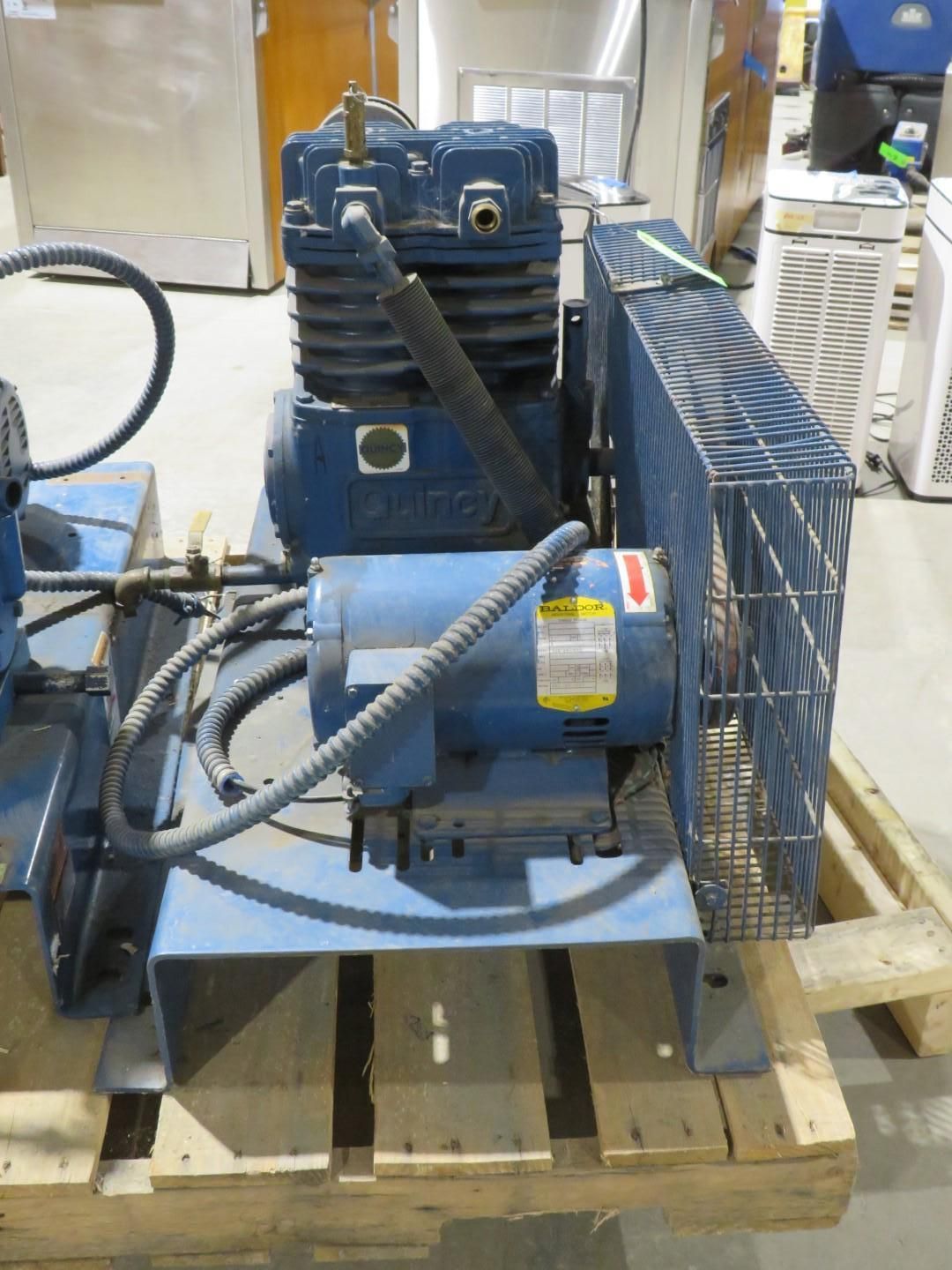Blue industrial air compressor on a wooden pallet.