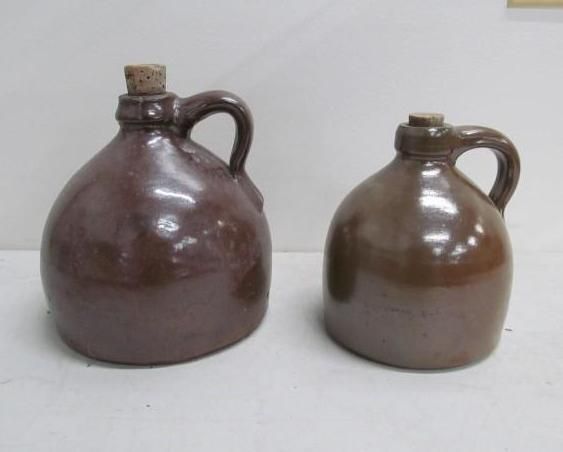 Two brown ceramic jugs with cork stoppers, side by side.