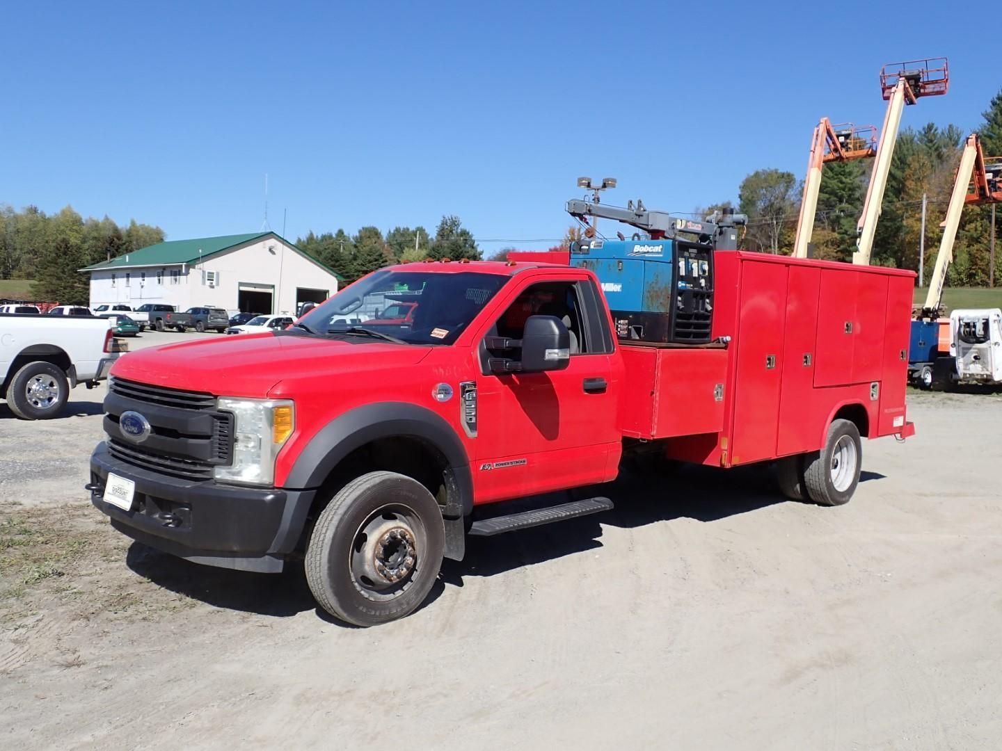 Red Ford work truck parked on gravel, with tool storage and welding equipment.