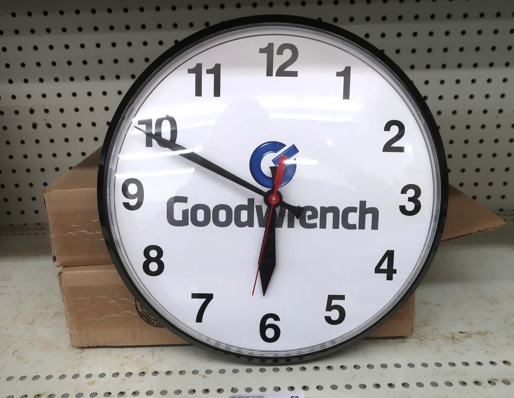 Goodwrench clock on a shelf, black rim, white face, black hands, and red second hand.