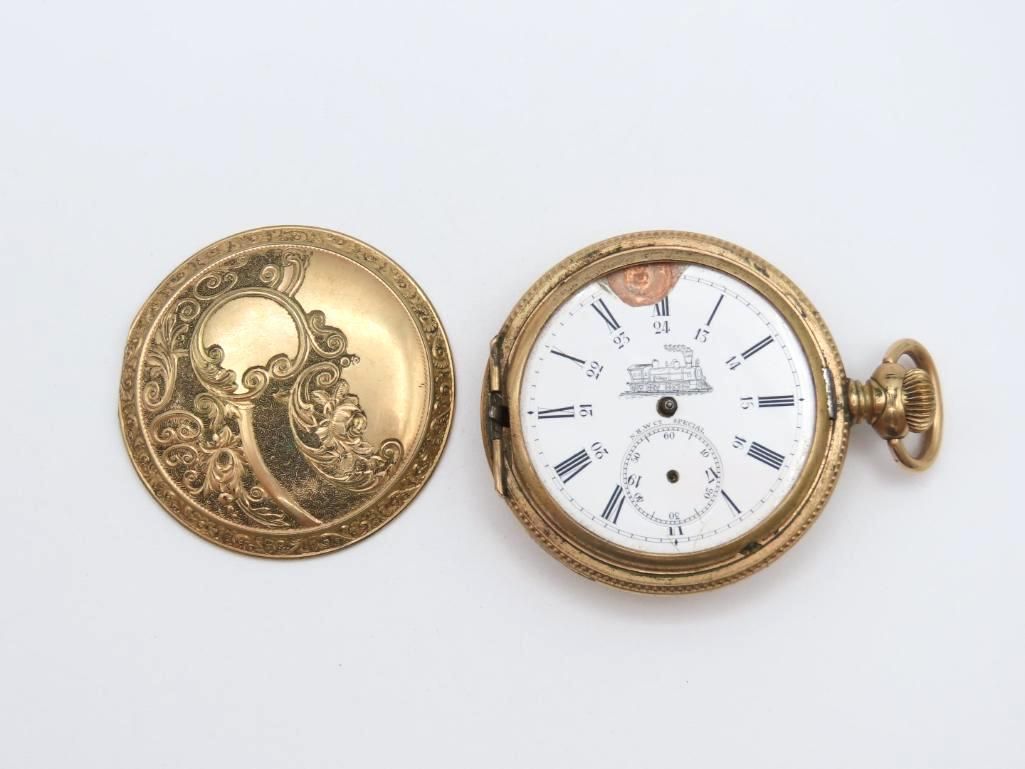 Open antique gold pocket watch with ornate details on case lid, face visible.