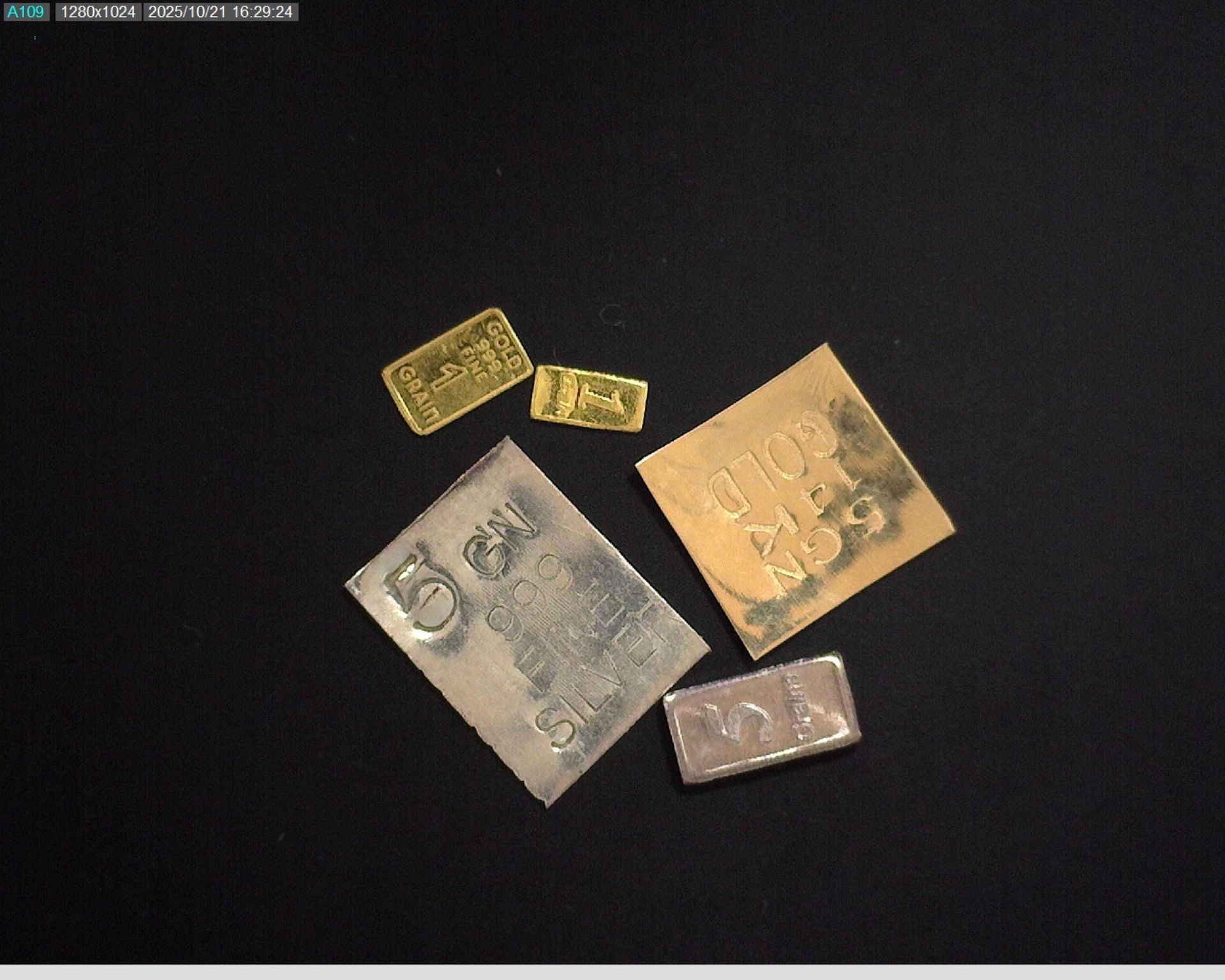 Assortment of gold, silver, and copper bullion bars on a black surface.