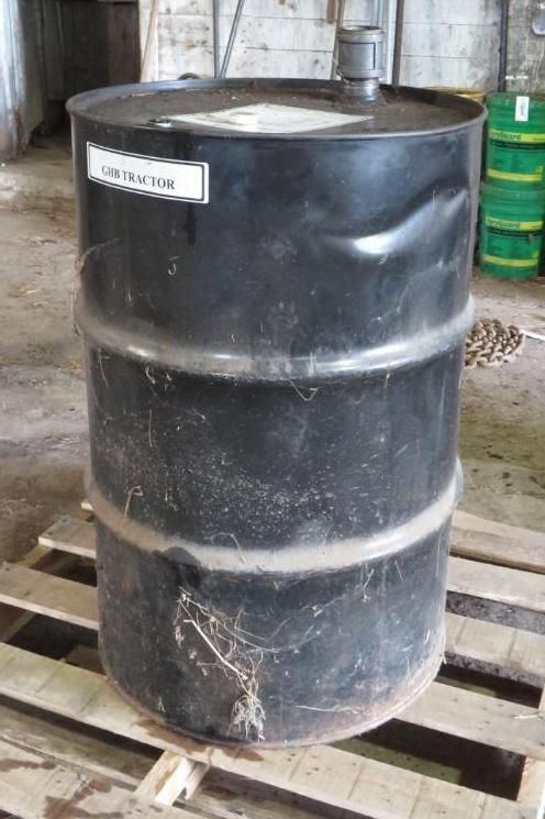 Black metal drum on a wooden pallet, with a label that says