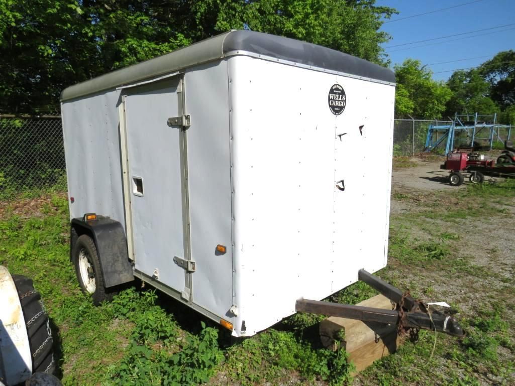 White enclosed utility trailer, parked on grass.