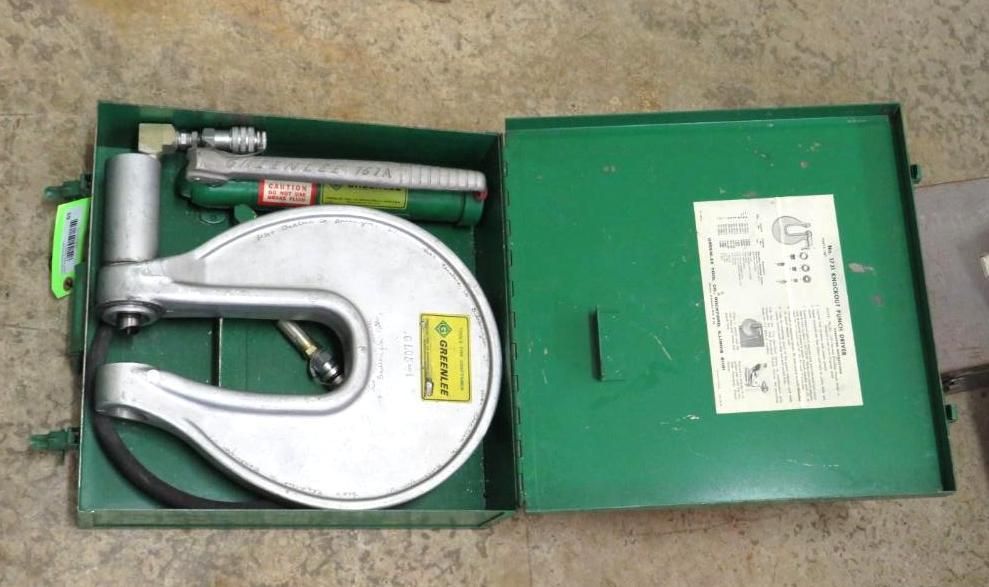 Green toolbox open, holding a silver hydraulic punch tool and related components.
