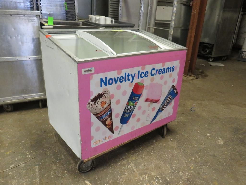 Pink and white novelty ice cream freezer with a glass top and caster wheels.