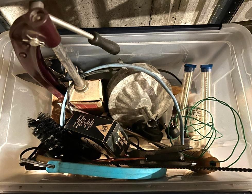 Clear plastic bin filled with tools, including brushes, a lever, vials, and a cleaning rod.