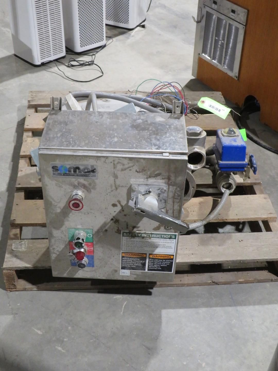 Metal industrial machine on a wooden pallet with wiring, valves, and a control panel, indoors.