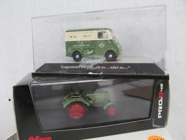 Model cars: a green and white van and a green tractor with red wheels, displayed in clear cases.
