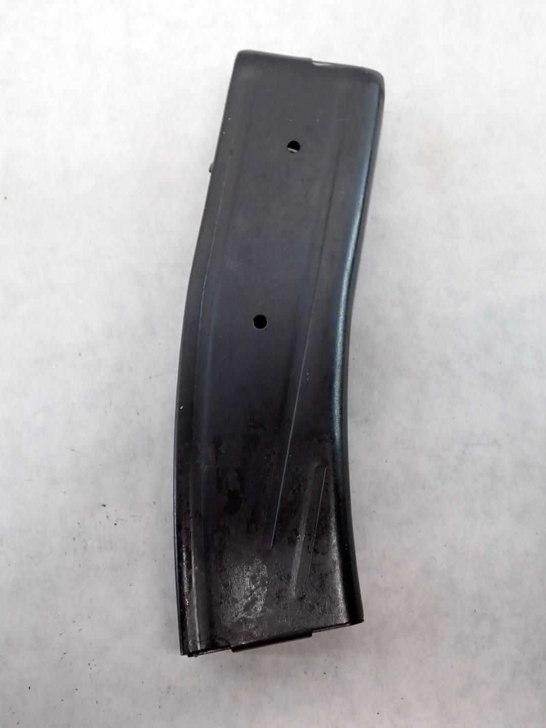 Black, curved rifle magazine with two visible holes, on a white surface.