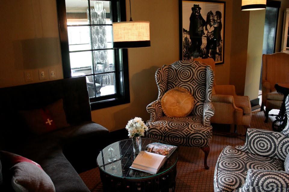 Stylish living room with chairs, black sofa, glass coffee table, and warm lighting.
