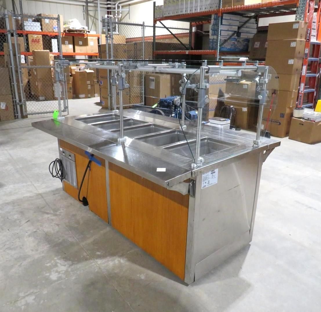Stainless steel buffet with sneeze guard in a warehouse.