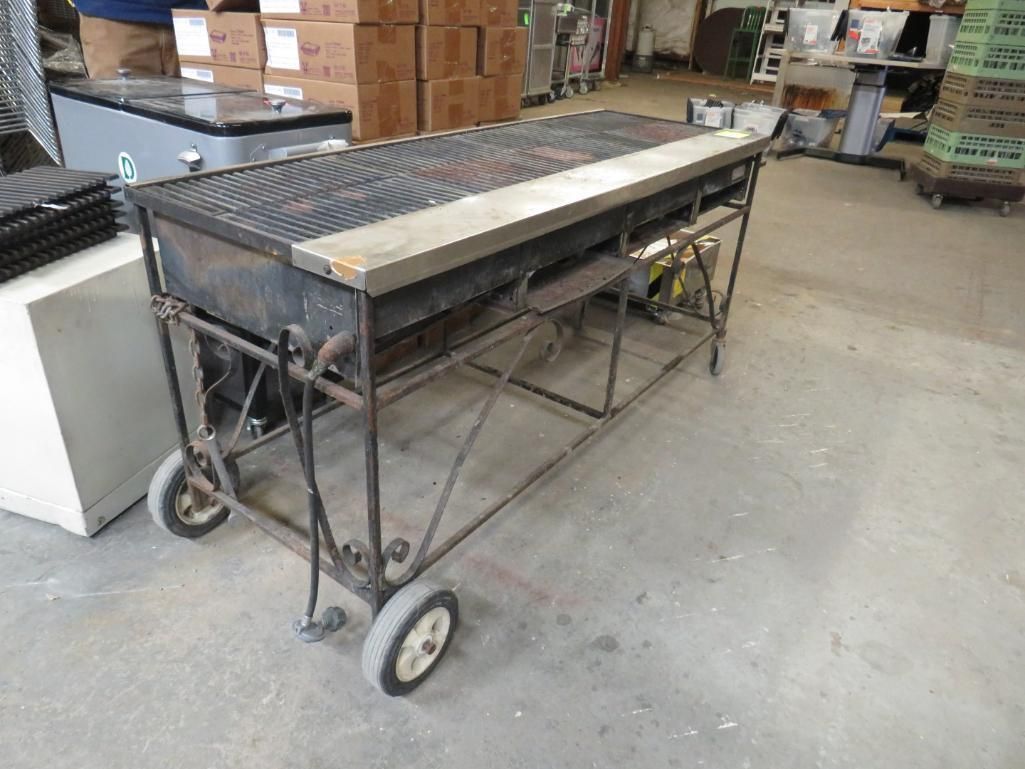 Large, black, wheeled grill with metal grate and stainless steel top.