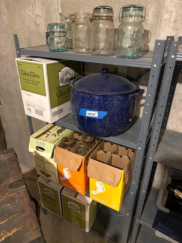 Metal shelf in a basement storing jars, boxes, and a blue pot.