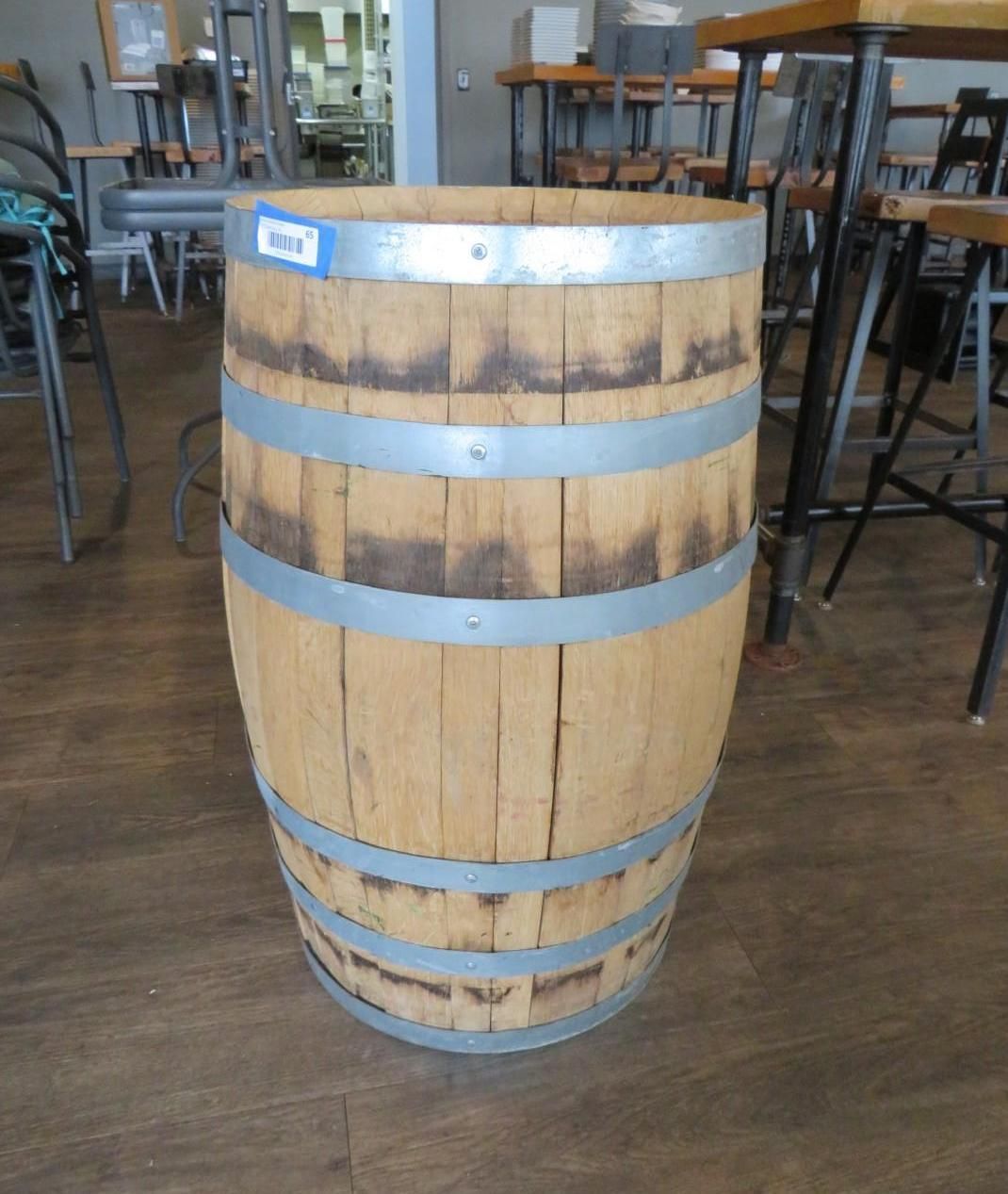 Wooden barrel with metal bands, standing on a wooden floor.