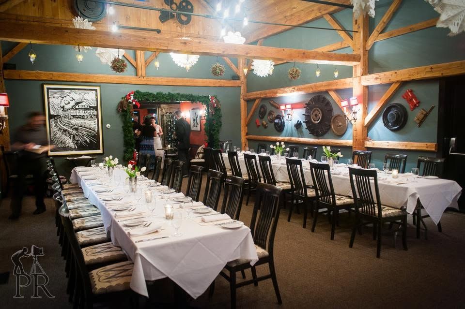 Rustic banquet hall with long white-clothed tables, chairs, and wood beams, set for a formal dinner