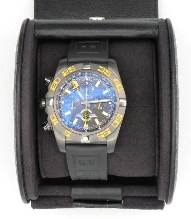 Breitling watch in a black travel case, dark gray case, blue face, gold numbers, black band.